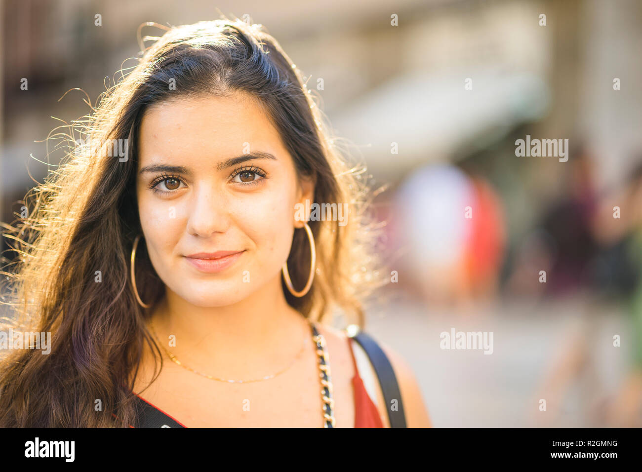 Portrait of young brunette teenager in sunny urban setting Stock Photo