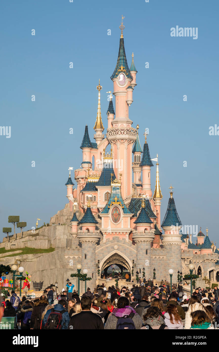 Disneyland Paris, France, November 2018: Tourist crowd in front of Sleeping Beauty's Castle with blue skies behind. Stock Photo