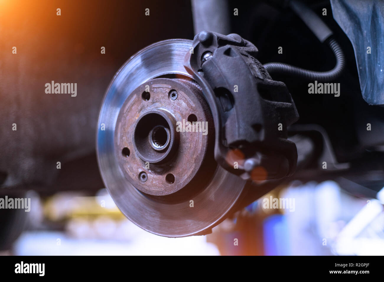 Car brake disk and caliper close up without wheel in cold colors with