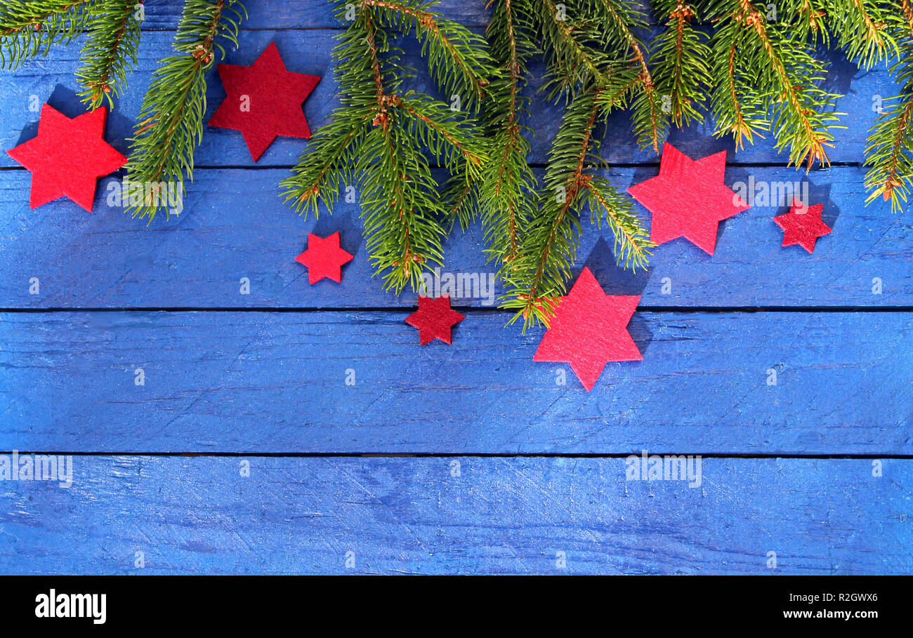 Christmas background with red stars and spruce branches on blue wood ...