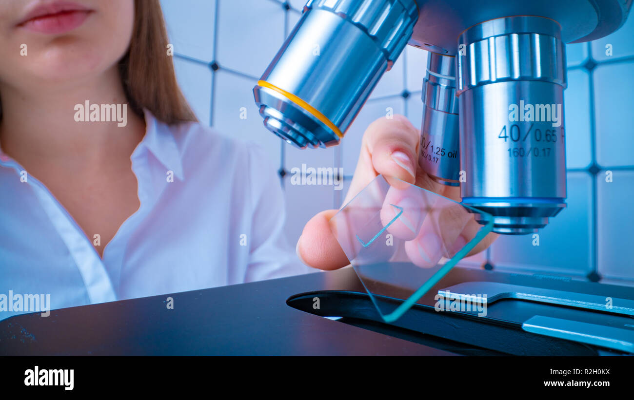 Scientist analyzing microscope slide at laboratory. Young woman ...