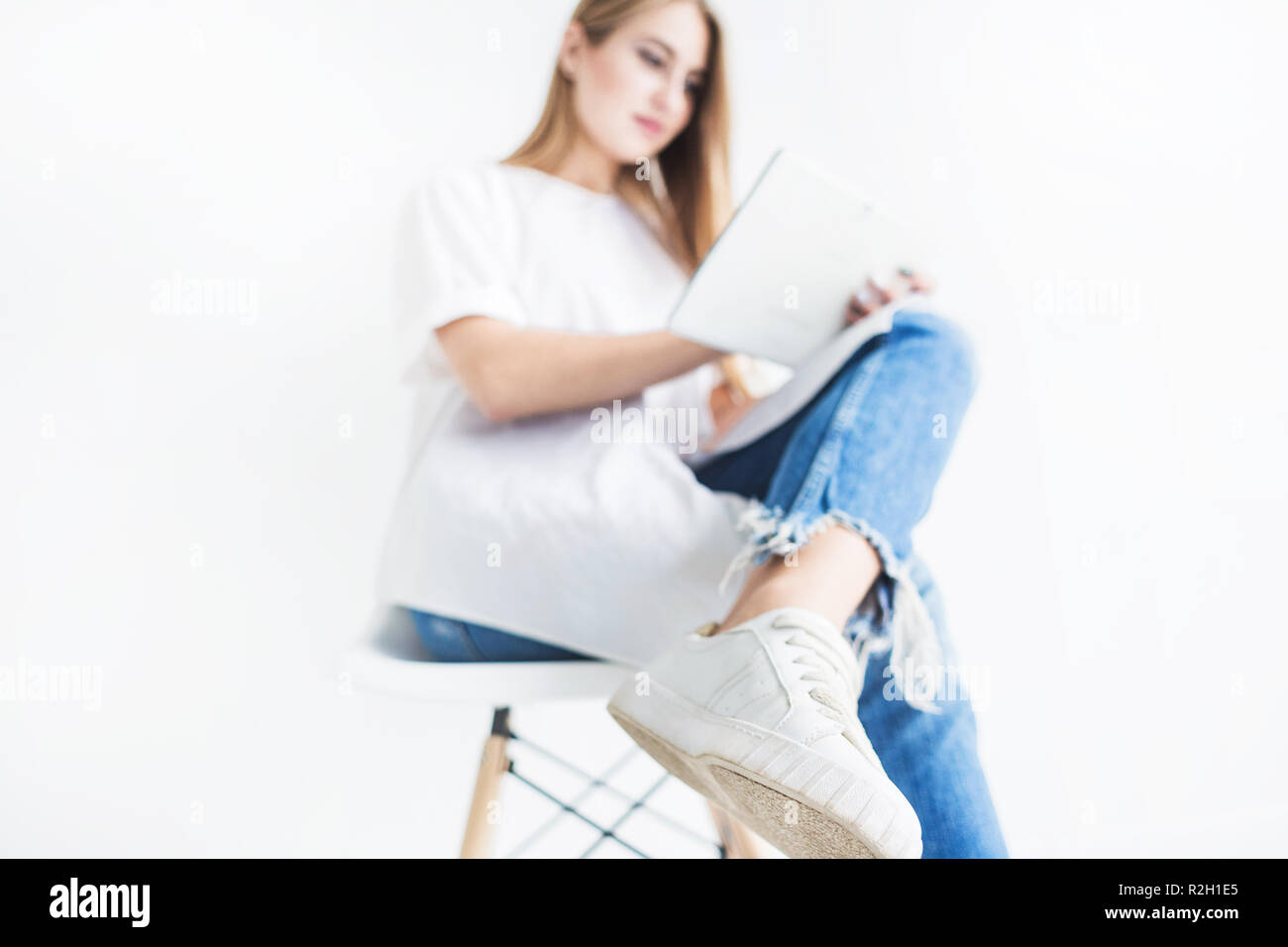 Portrait of a young stylish blonde girl in a white T-shirt and blue ...