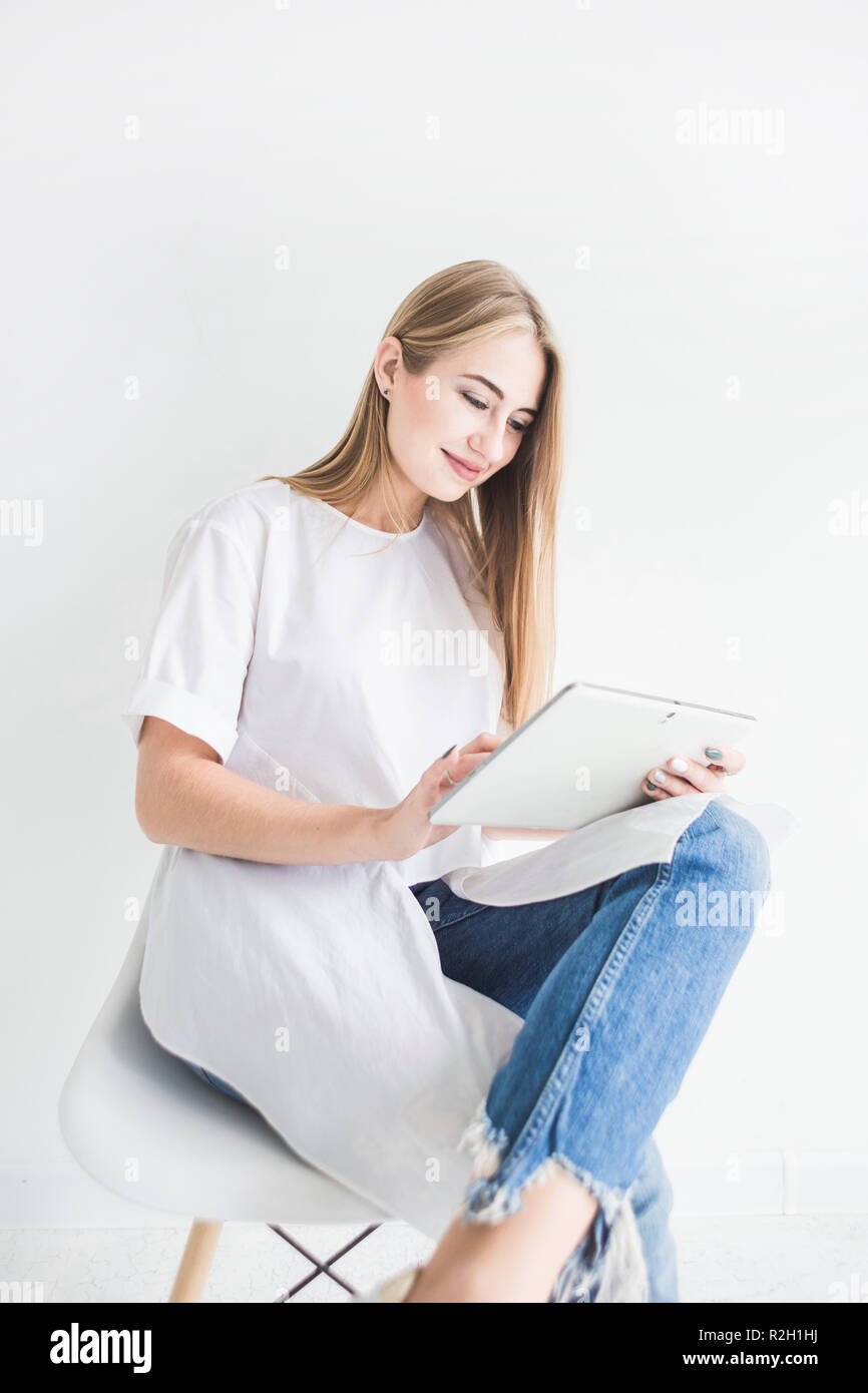 Portrait of a young stylish blonde girl in a white T-shirt and blue ...