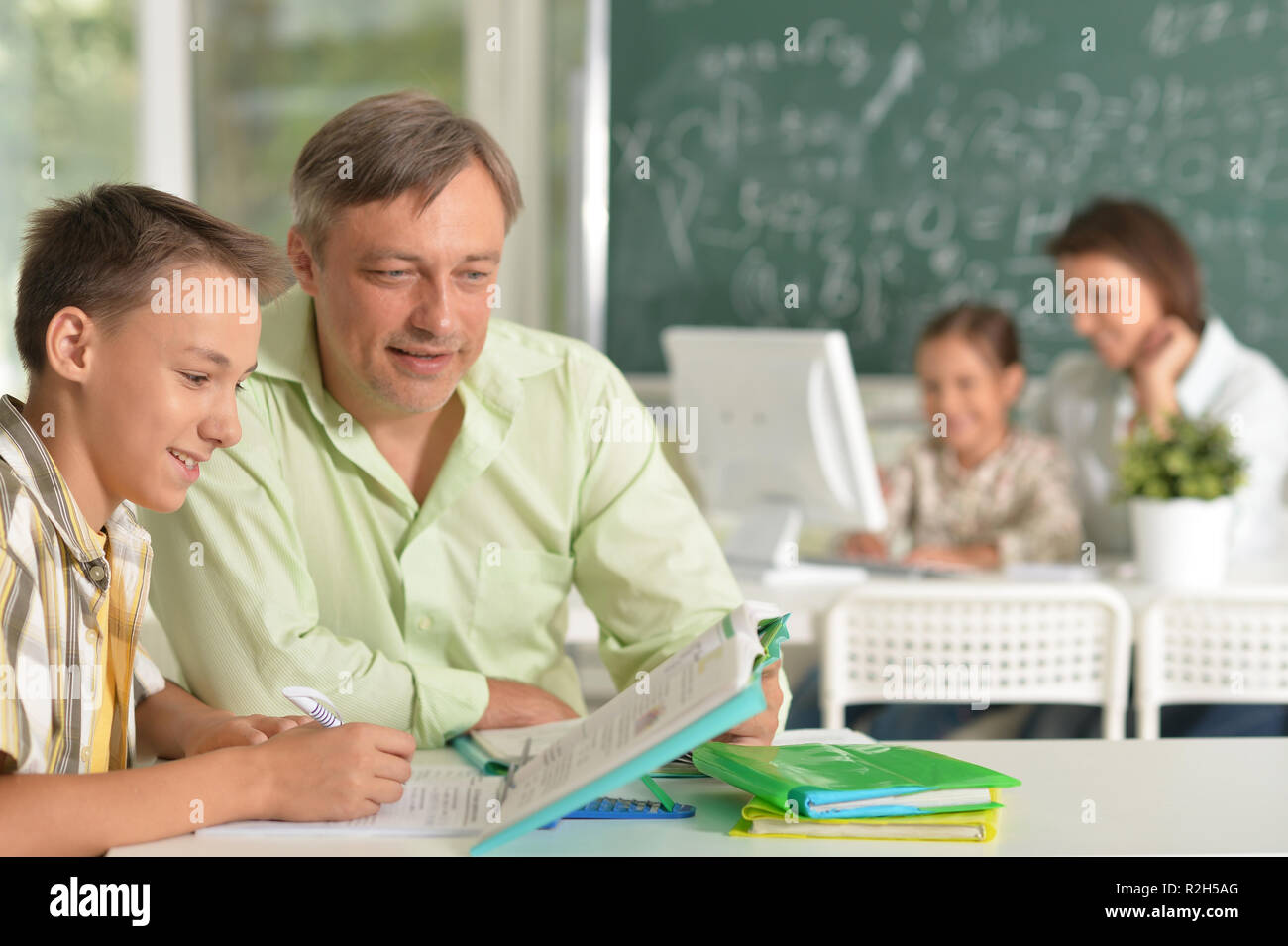 Father helping his son doing homework in classroom Stock Photo - Alamy
