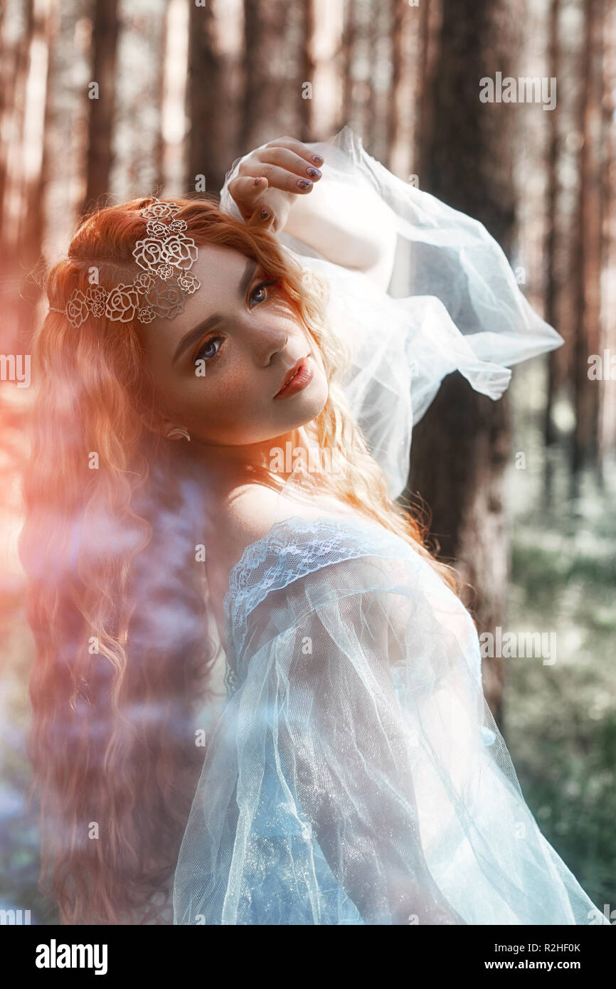 Beautiful redhead woman forest nymph in a blue transparent light dress in  the woods spinning in dance. Red hair girls. Art fashion portrait of fairy  w Stock Photo - Alamy