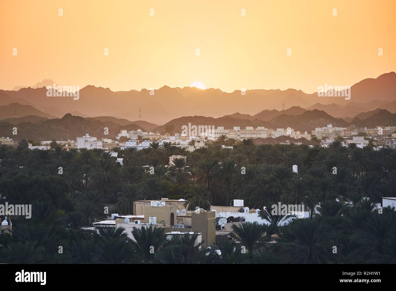 City against mountain range at idyllic sunset. Nizwa in Sultanate of Oman. Stock Photo