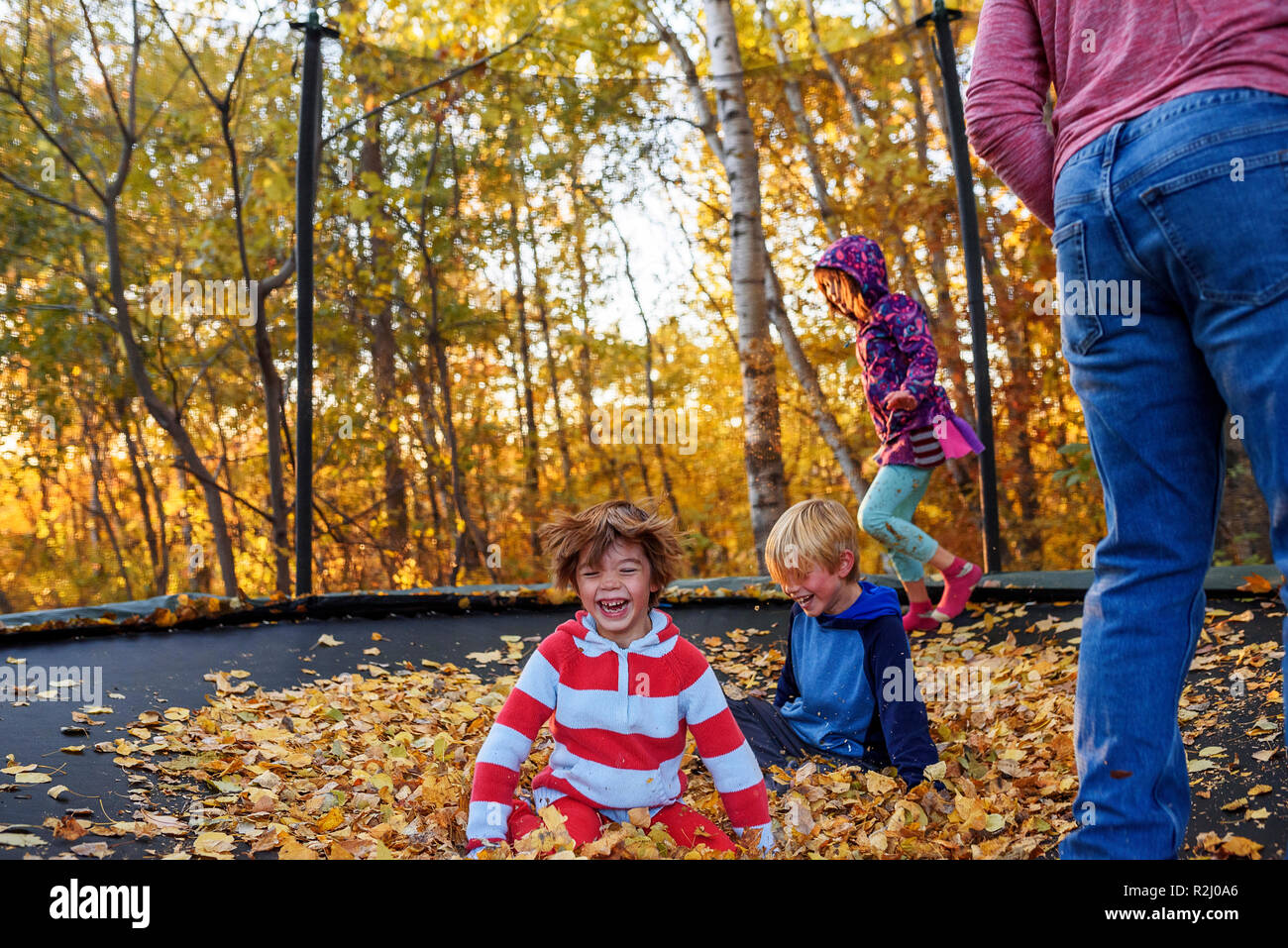 Three children and their father playing on a trampoline covered in