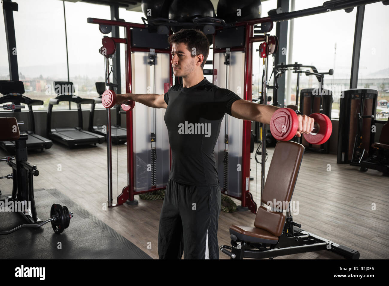 Man standing in a gym lifting weights Stock Photo Alamy