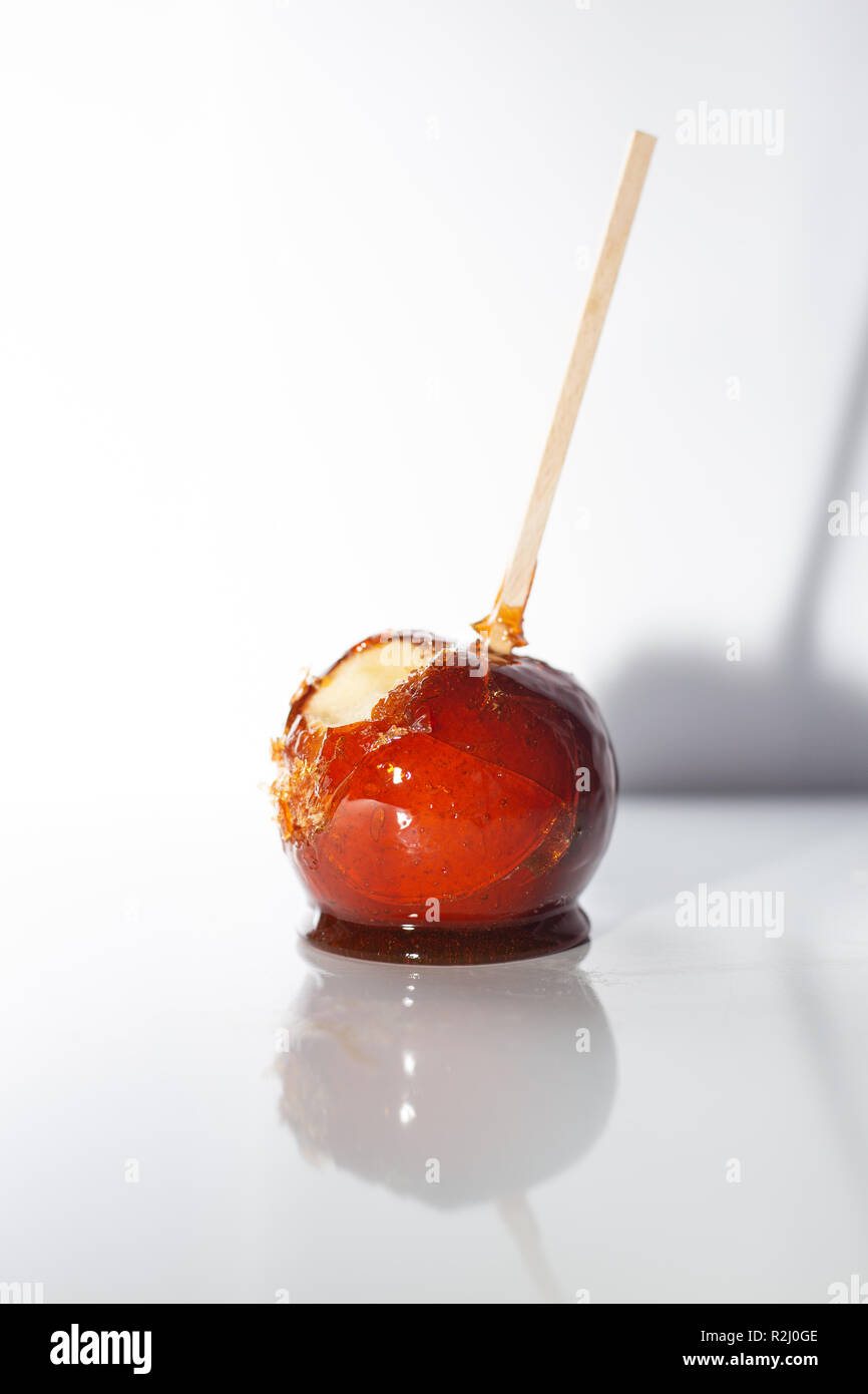 A candy apple with a bitten taken out of it, with white backround. Stock Photo