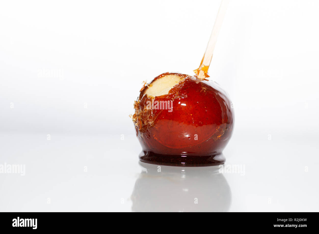 A candy apple with a bitten taken out of it, with white backround. Stock Photo