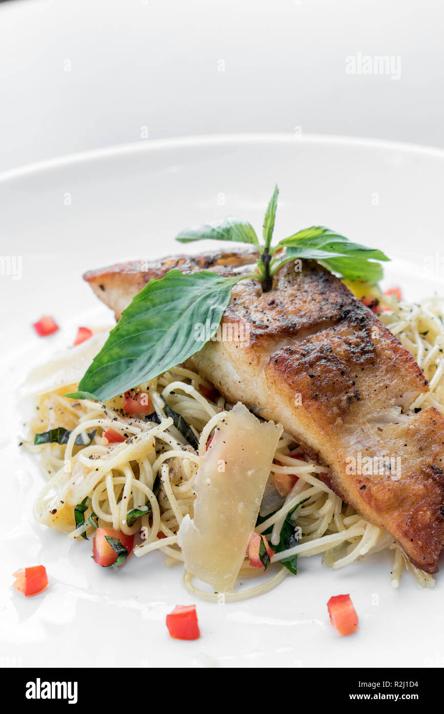 fresh cod fish fillet on mixed vegetable and parmesan spaghetti pasta Stock Photo
