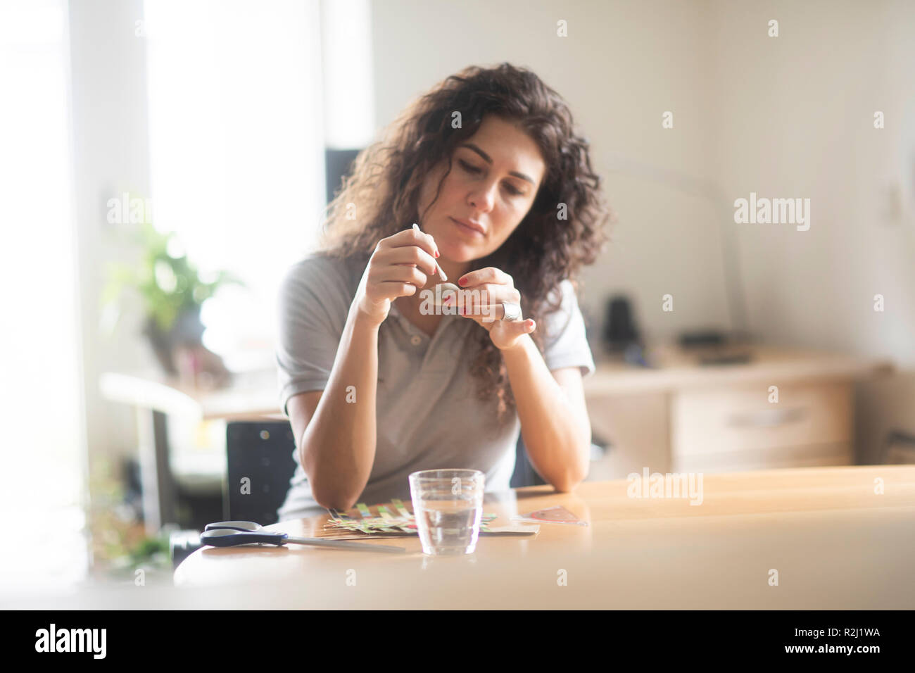 Woman sitting at a table painting a stone Stock Photo