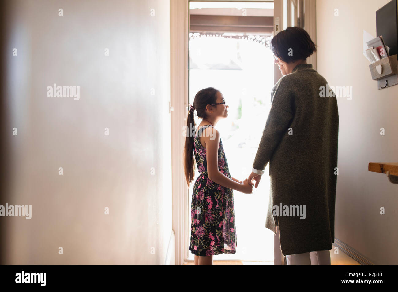 Affectionate mother and daughter holding hands in doorway Stock Photo