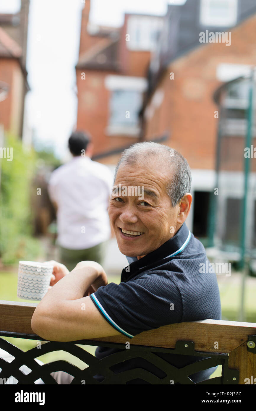 Portrait smiling senior man drinking tea in yard Stock Photo