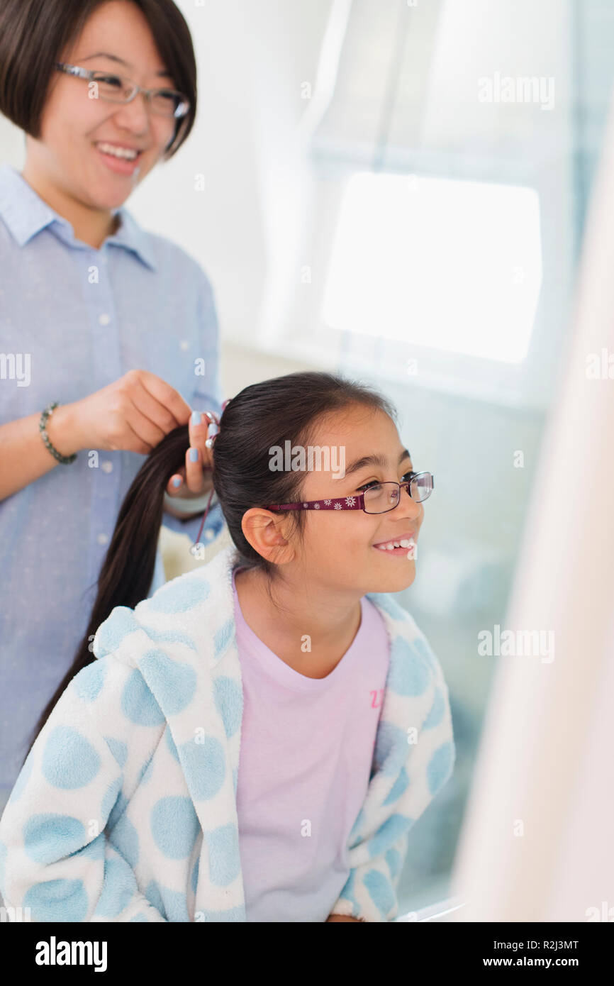 Mother fixing daughters hair in bathroom Stock Photo