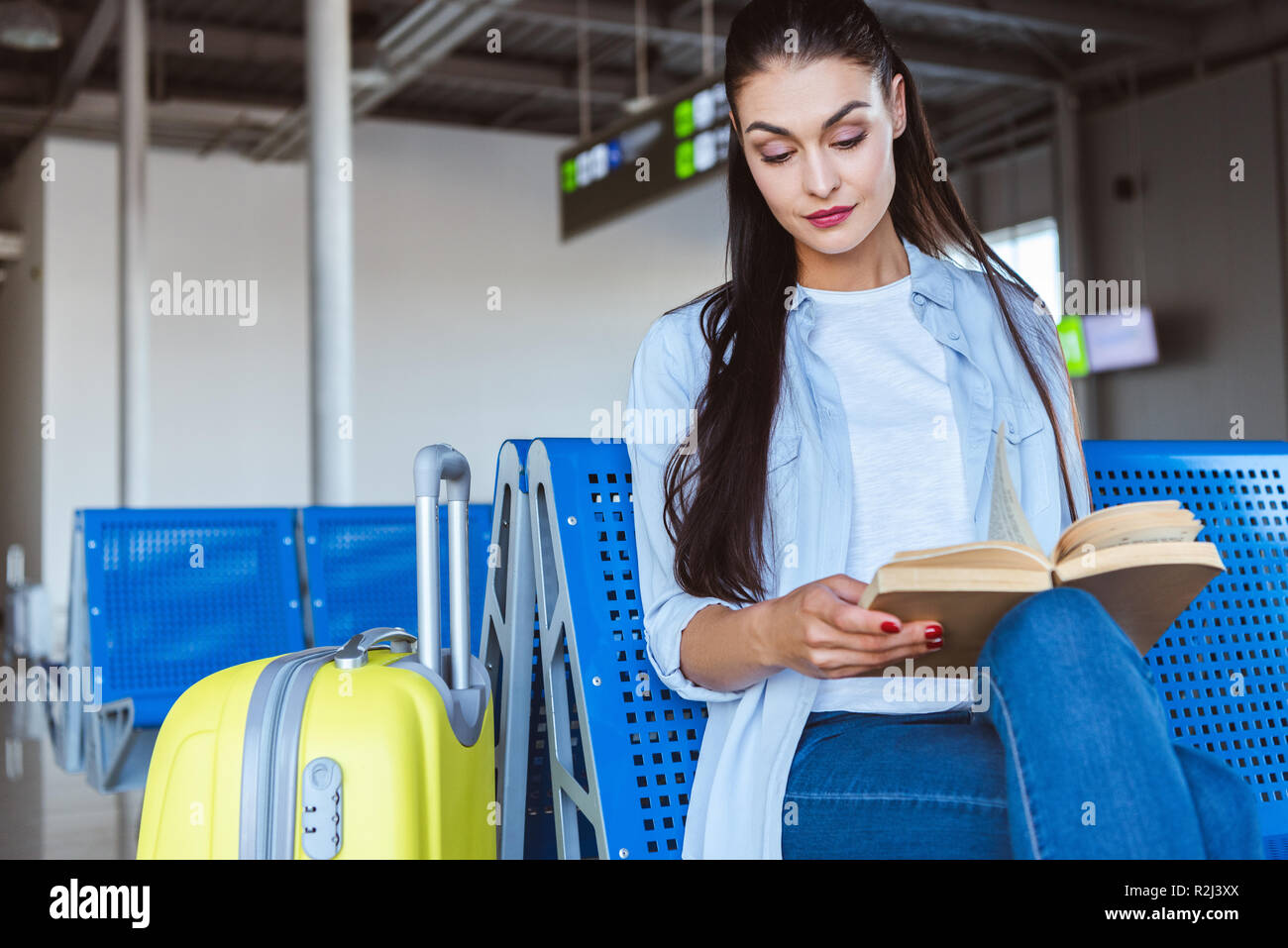 Woman reading book and waiting for her plane in the airport Stock Photo