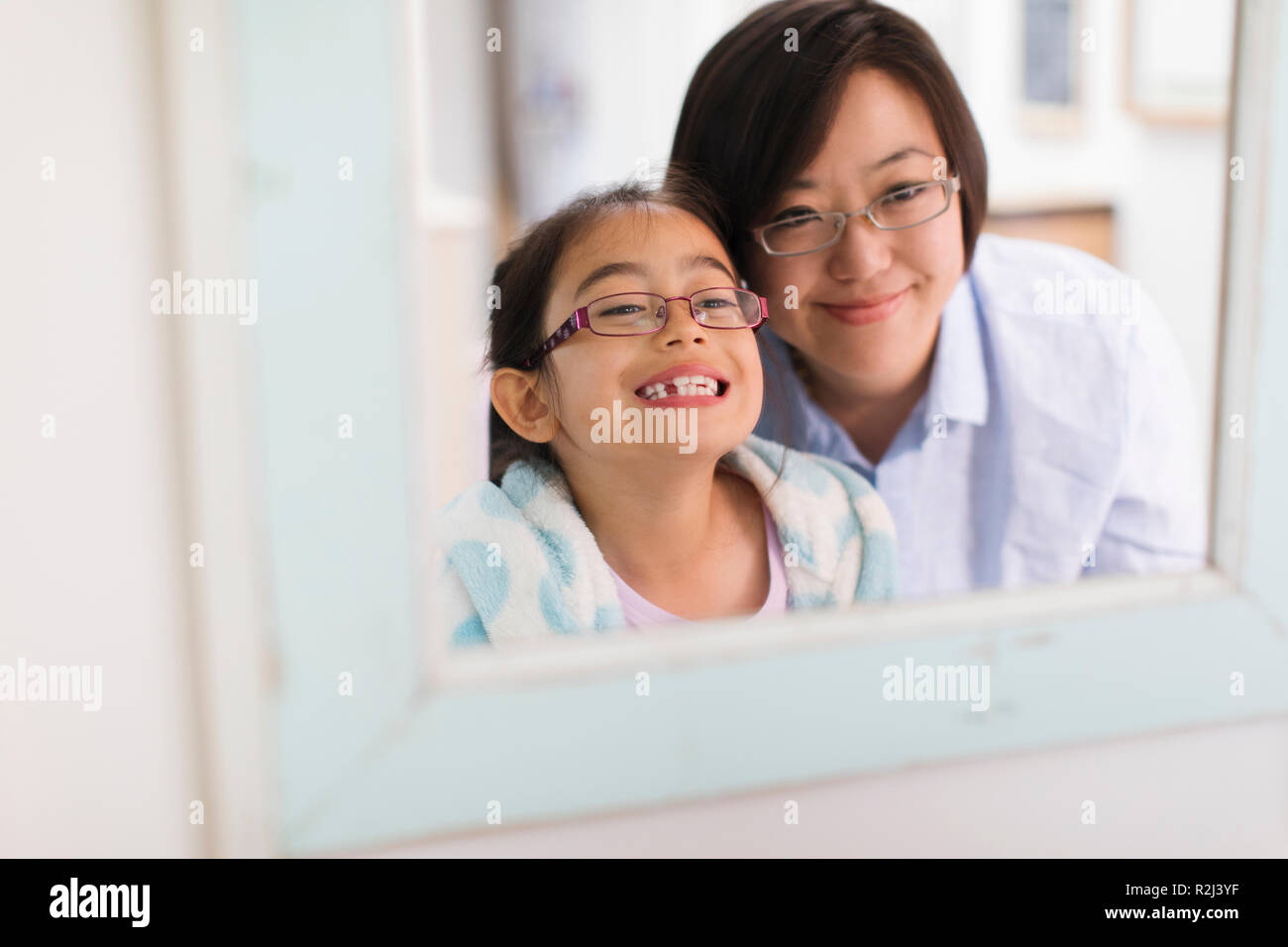 Mother watching daughter showing teeth in bathroom mirror Stock Photo