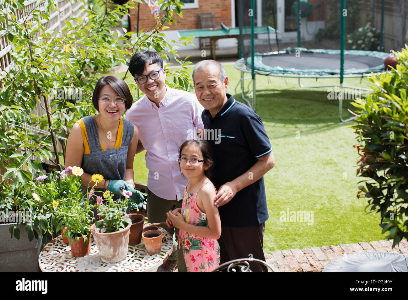 Portrait smiling multi-generation family gardening, potting flowers in sunny yard Stock Photo