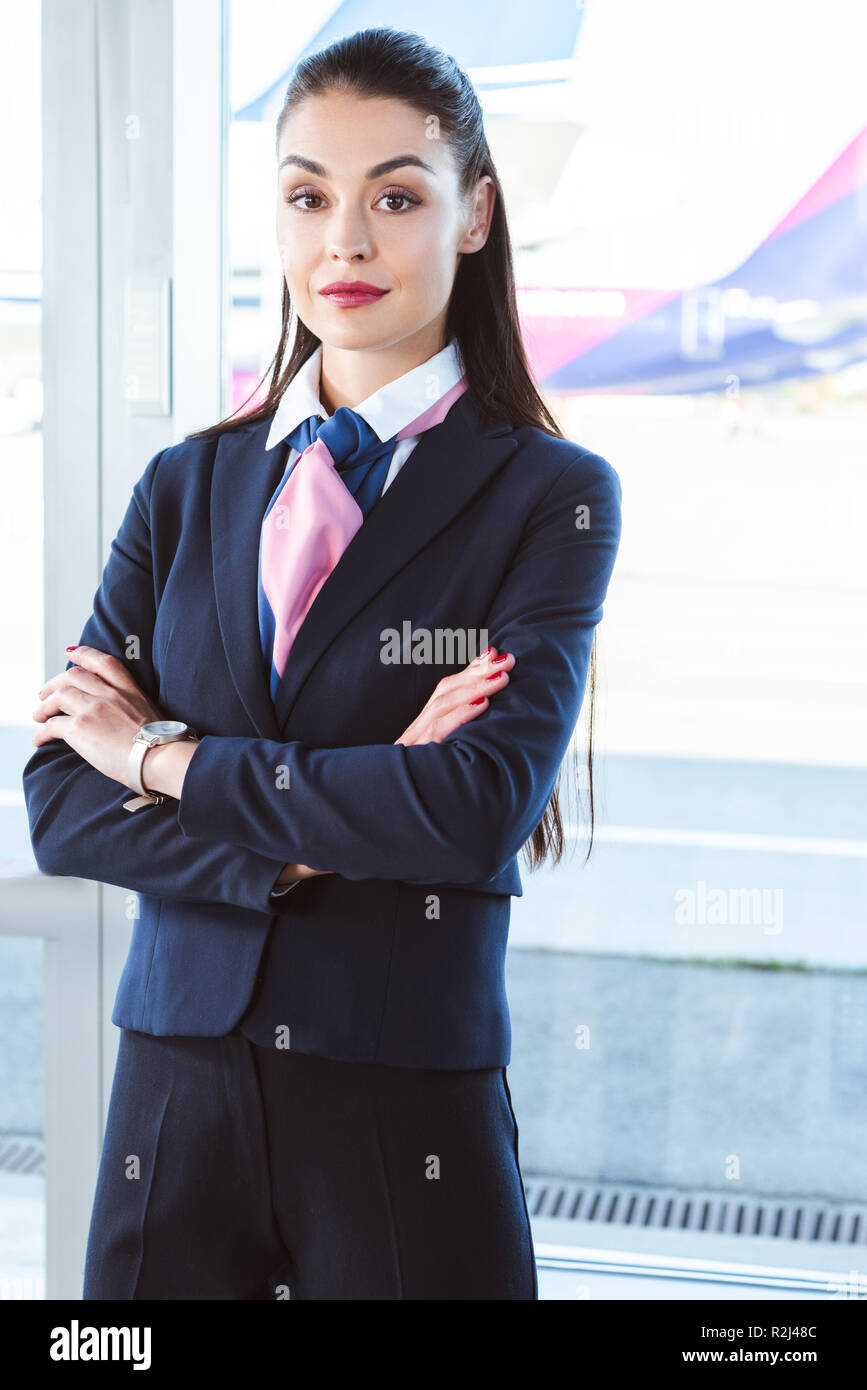 adult female airport worker standing with arms crossed near window