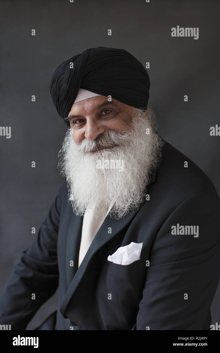 Portrait smiling, confident well-dressed senior man with beard in turban Stock Photo