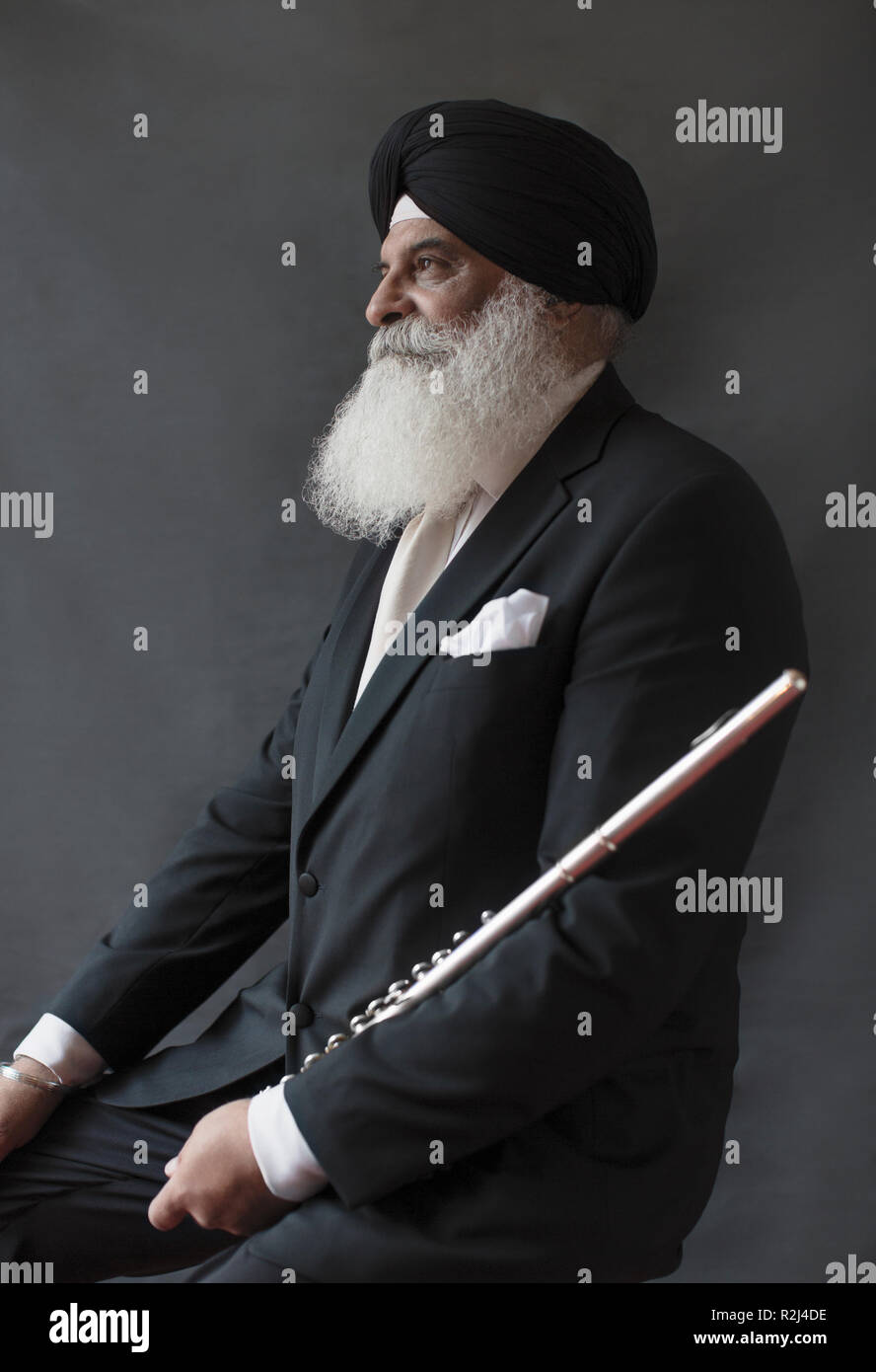 Portrait serious, well-dressed senior man in turban holding flute Stock Photo