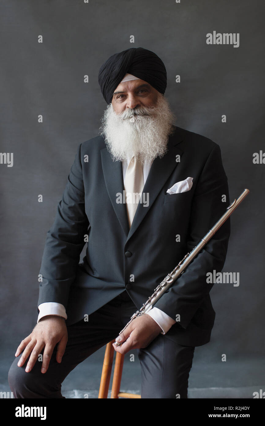 Portrait confident, well-dressed senior man in turban holding flute Stock Photo