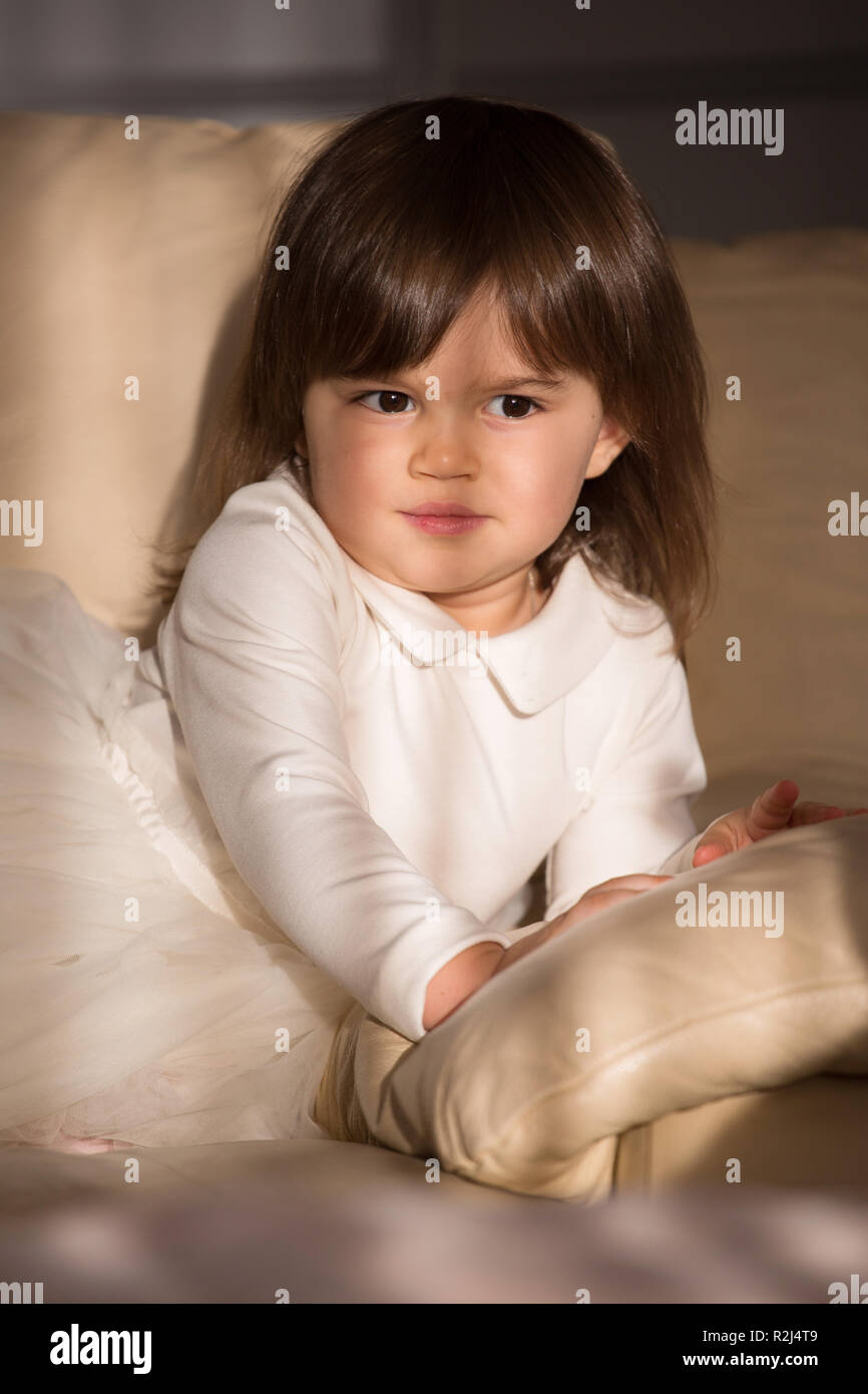 Pretty baby girl with brown hair in white dress Stock Photo