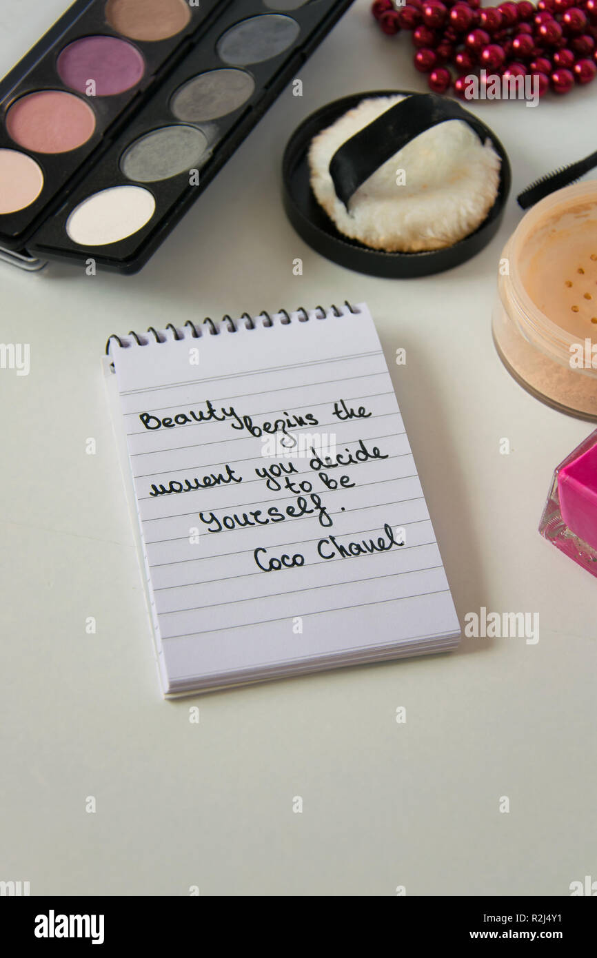 Coco Chanel quotes written on a block note, pearl accessories and
