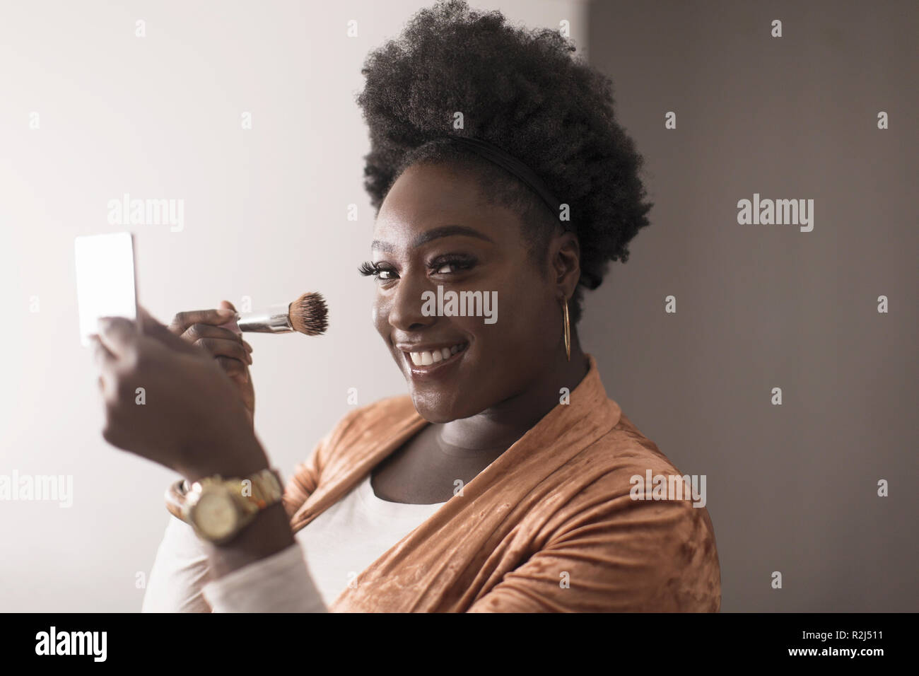 Portrait smiling, confident woman applying makeup in compact mirror Stock Photo