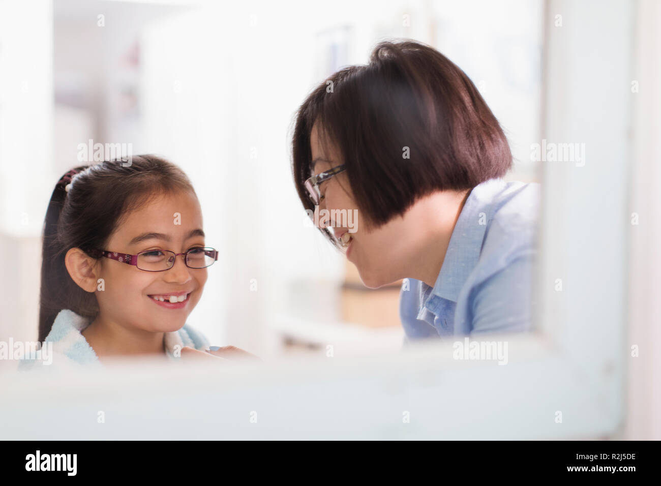 Reflection of mother and daughter in bathroom mirror Stock Photo