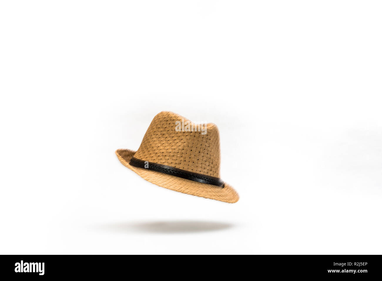 At the Drop of a Hat. A straw panama hat falling against a white background. Stock Photo
