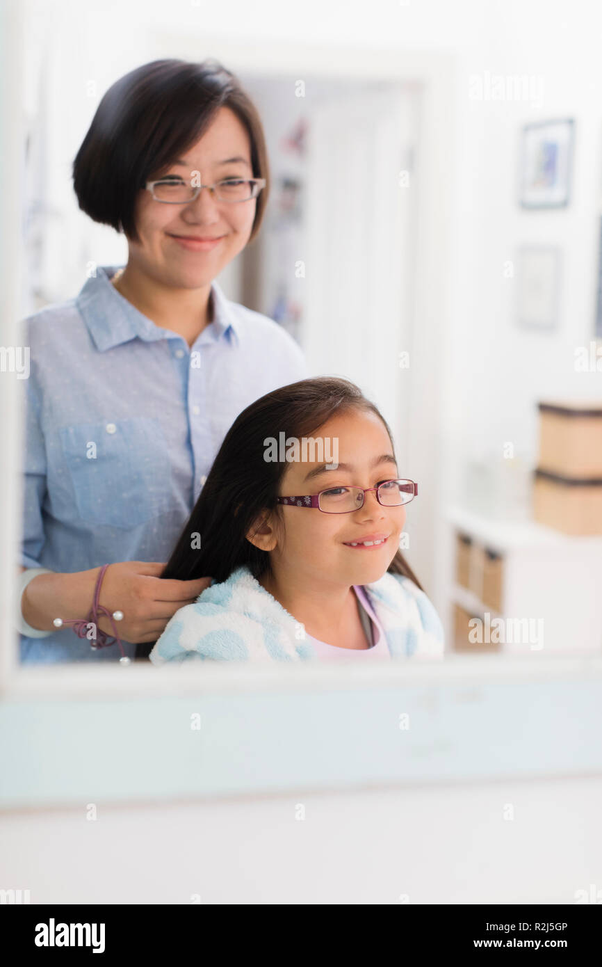 Mother fixing daughters hair in bathroom mirror Stock Photo