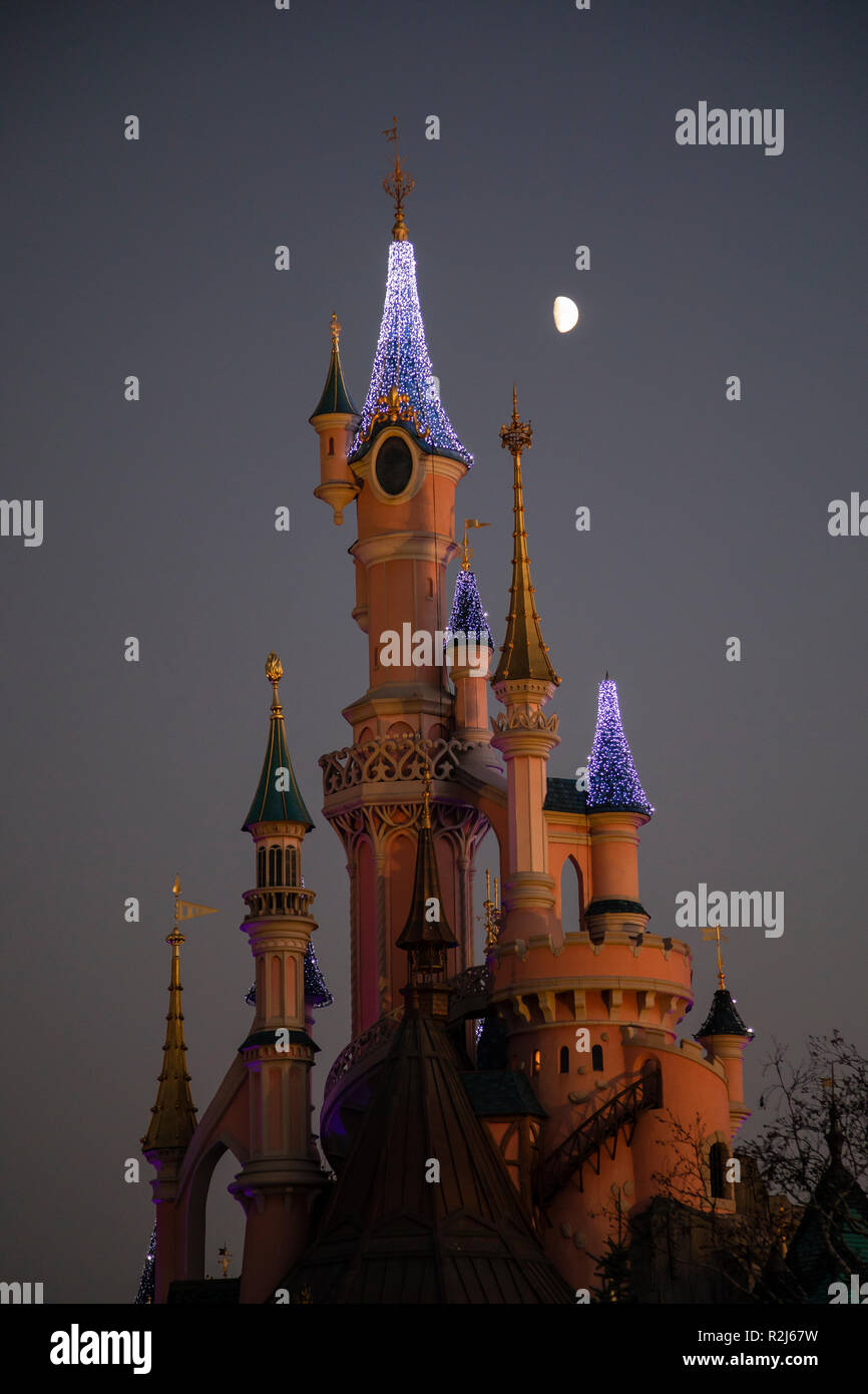 Disneyland Paris, France, November 2018: Moon rising over Sleeping Beauty's Castle at night. Stock Photo