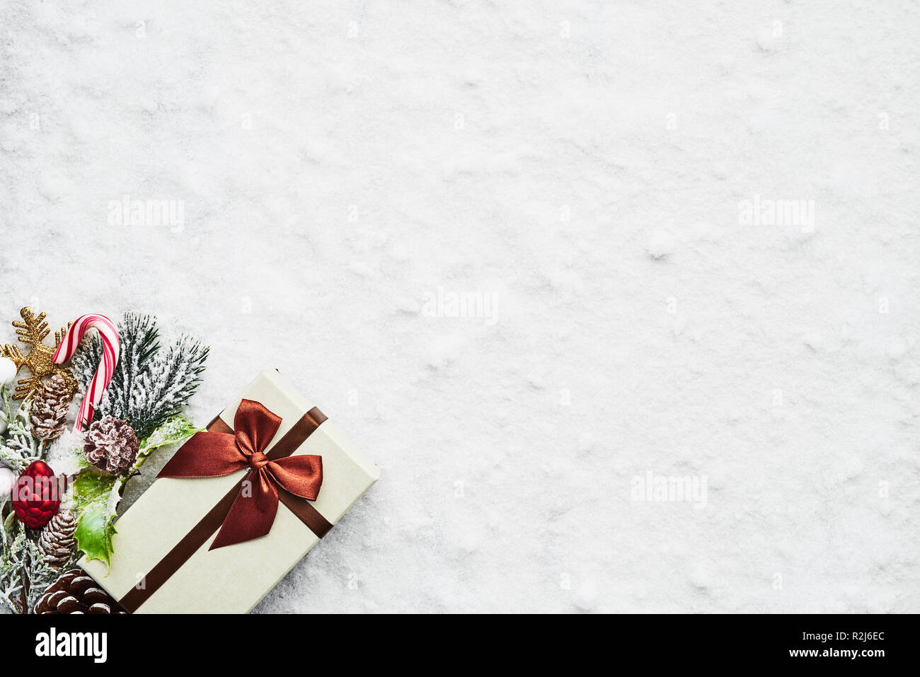 Top view of wrapped Christmas gift box with maroon ribbon and decoration on the snow. Copy space for text. Stock Photo