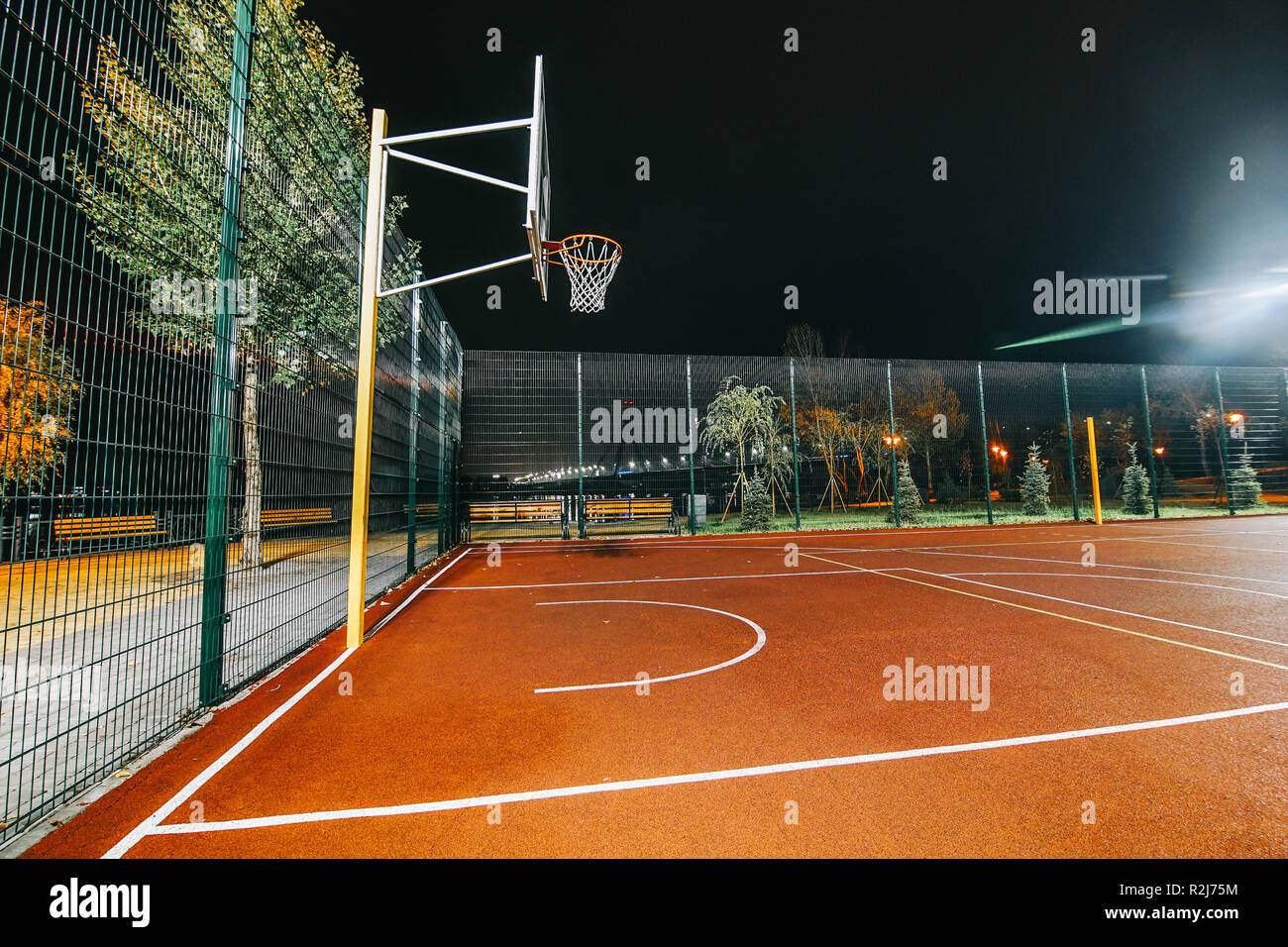 Illuminated basketball playground with red pavement, modern new