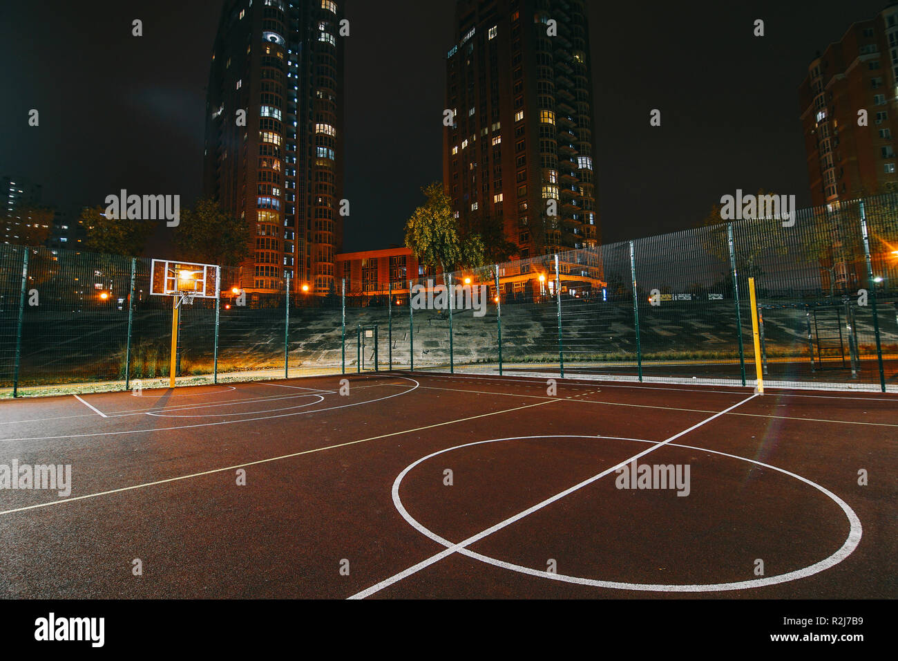 Illuminated basketball playground with red pavement, modern new