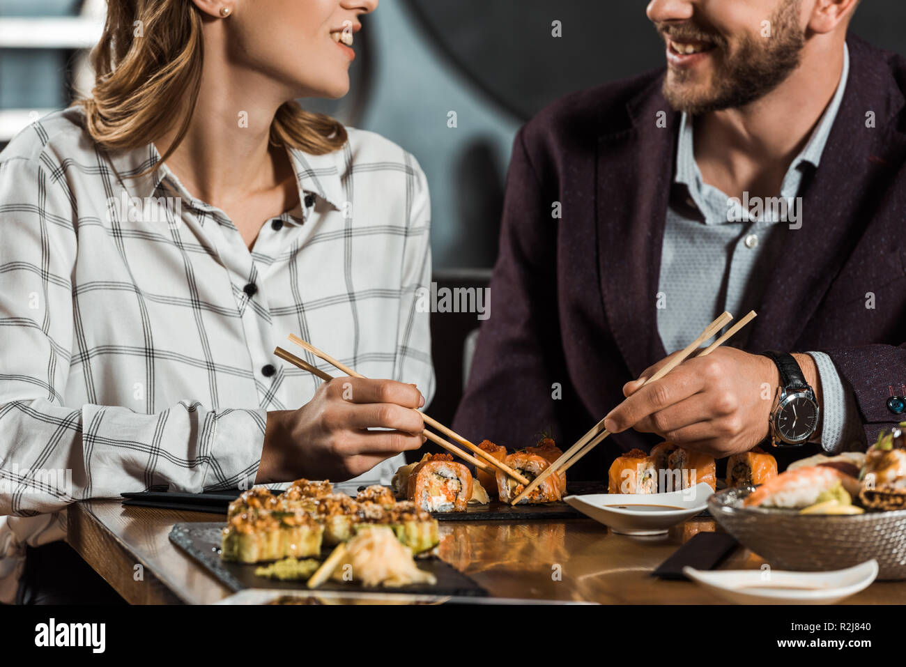 Partial view of smiling couple eating sushi in restaurant Stock Photo