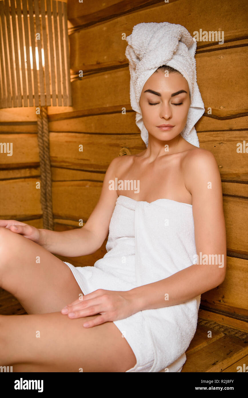 beautiful young woman sitting with closed eyes and relaxing in steam