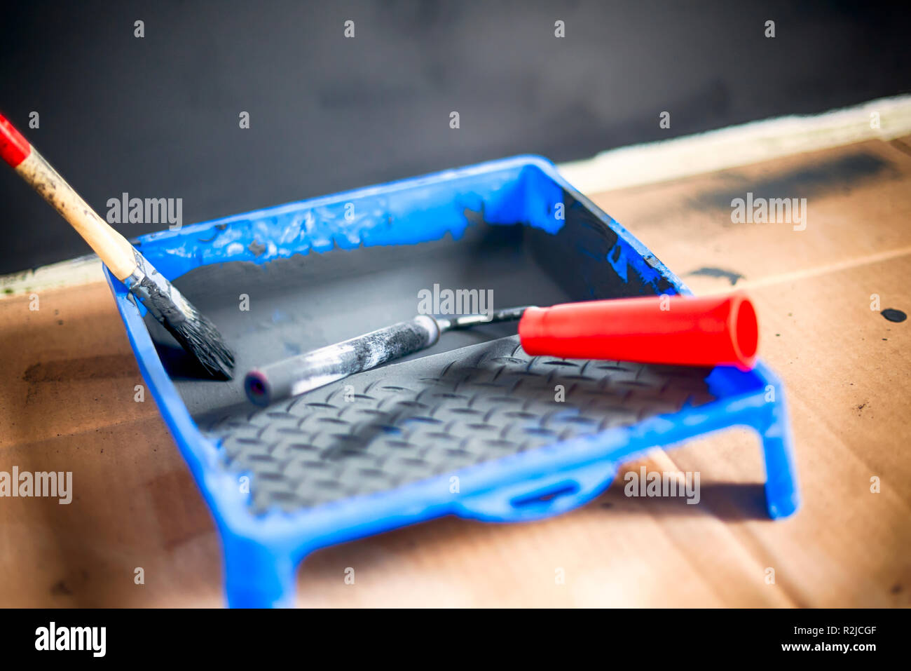 Paint roller and paint brush in paint tray with black paint. Close-up. Stock Photo