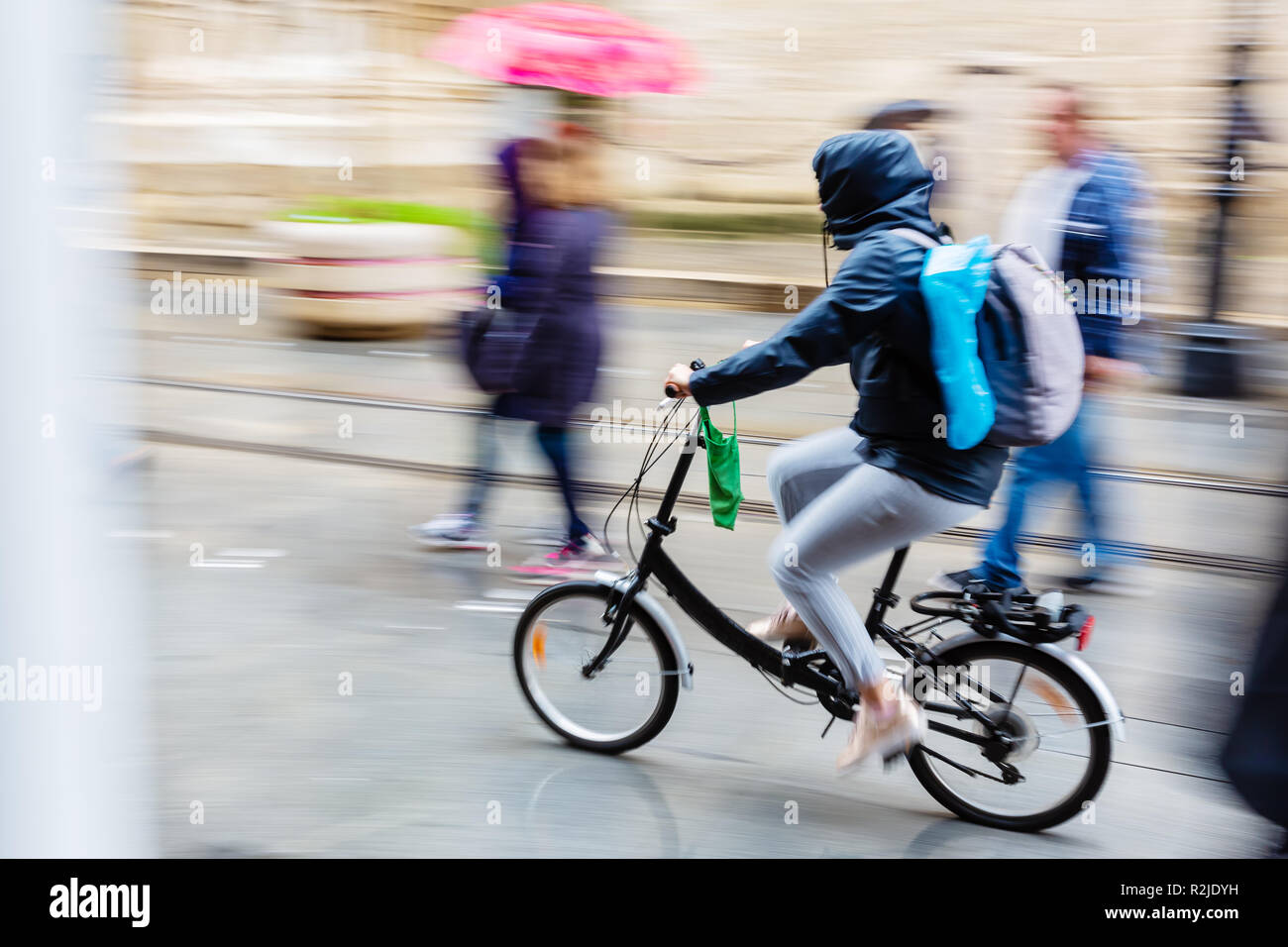 bicycle rider in the rainy city, picture made with motion blur effect ...