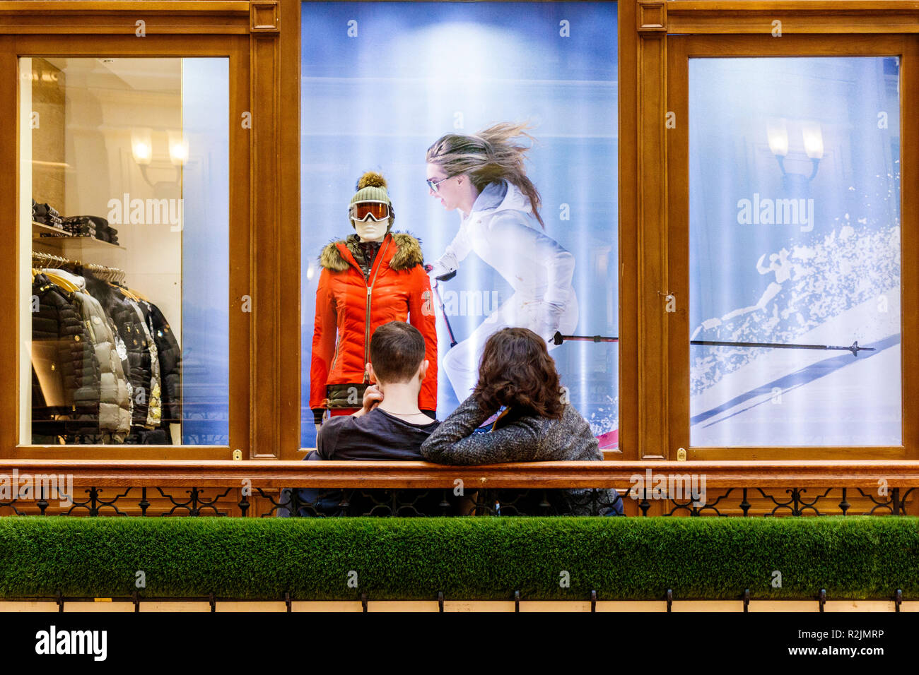A Young Couple Sitting On A Bench Outside A Winter Wear Clothing