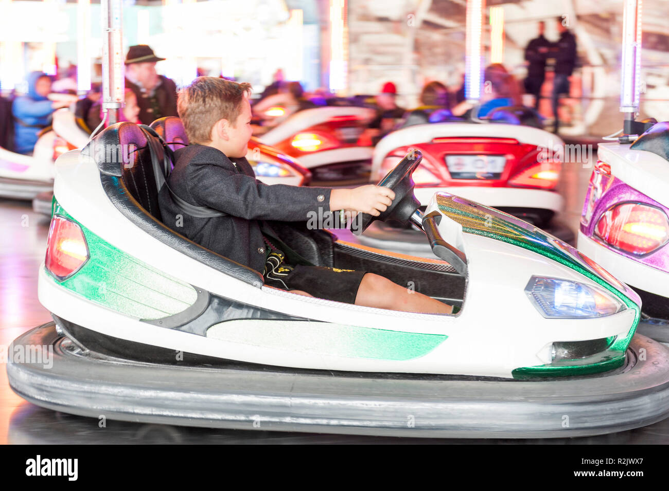 ten-year-old boy in traditional clothes driving bumper car, Munich, Oktoberfest Stock Photo
