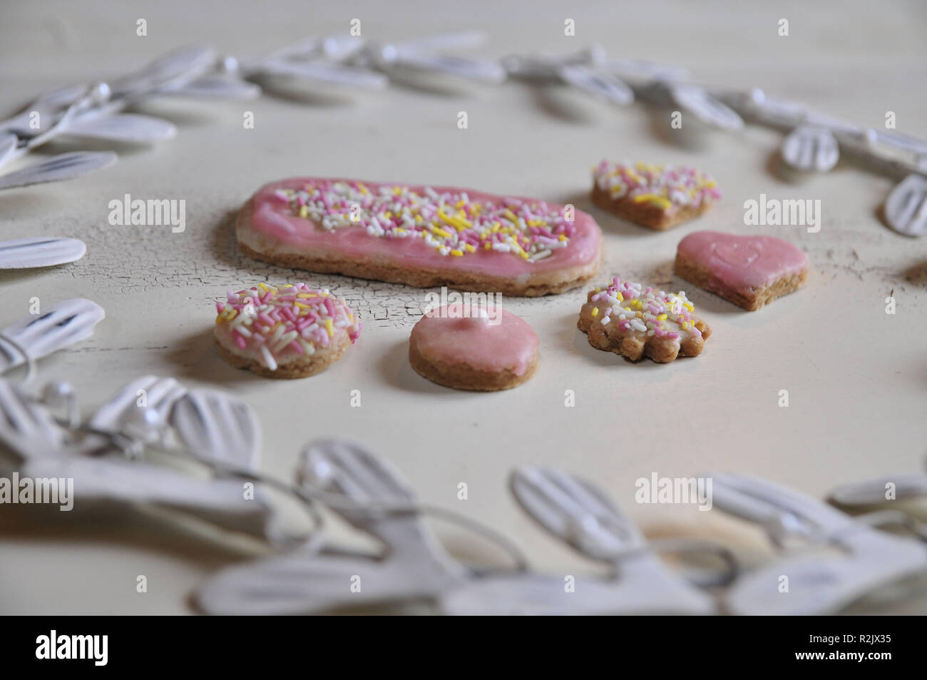 Cookies with pink fondant coating and colorful caster sugar with white metal wreath Stock Photo