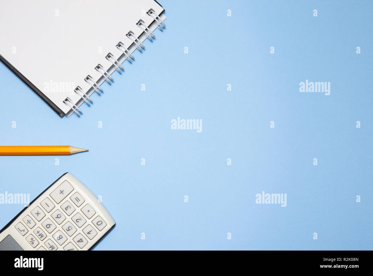 Notepad, calculator and pencil on blue background Stock Photo
