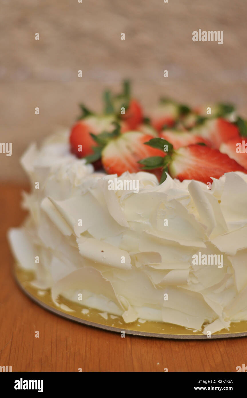 White chocolate strawberry cake with fresh strawberry fruits on top and white chocolate pieces around Stock Photo