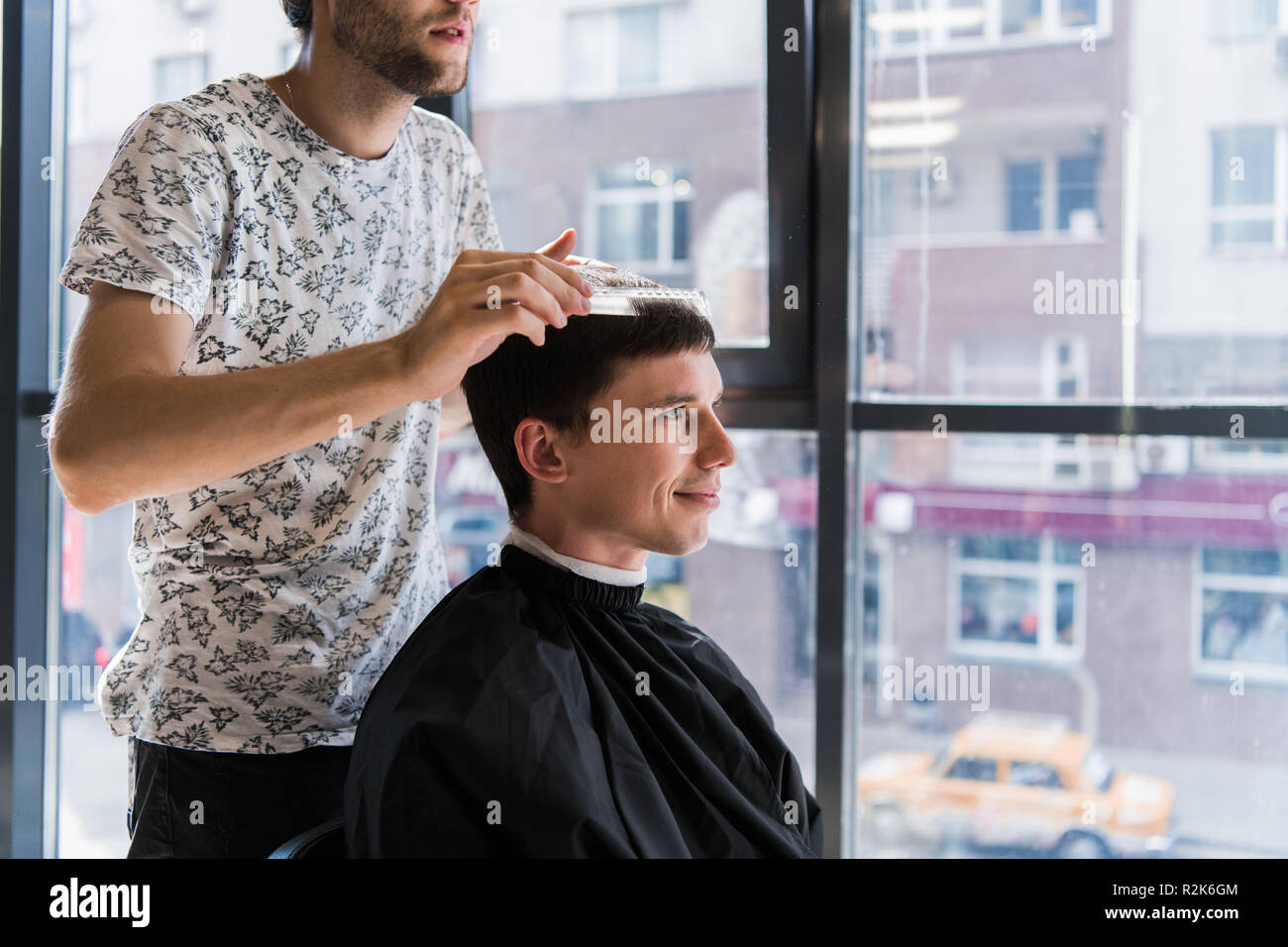 Man getting haircut at barber shop. Hairdresser styling hair of customer at salon. Stock Photo