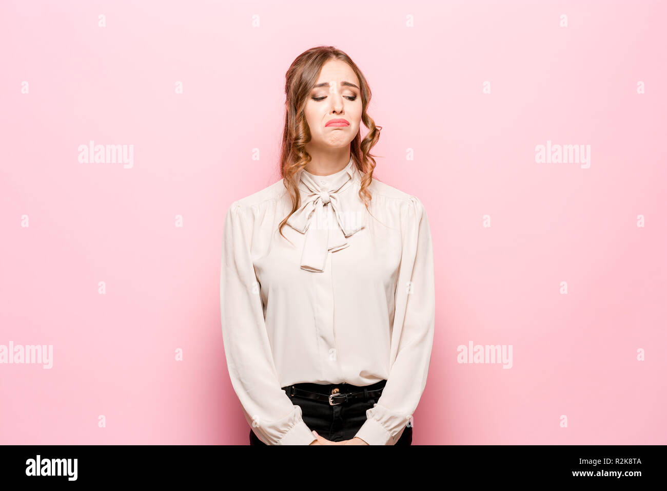 Portrait of displeased upset female frowns face as going to cry, being discontent and unhappy as cant achieve goals, isolated over pink studio background. Dissapointed young woman has troubles Stock Photo