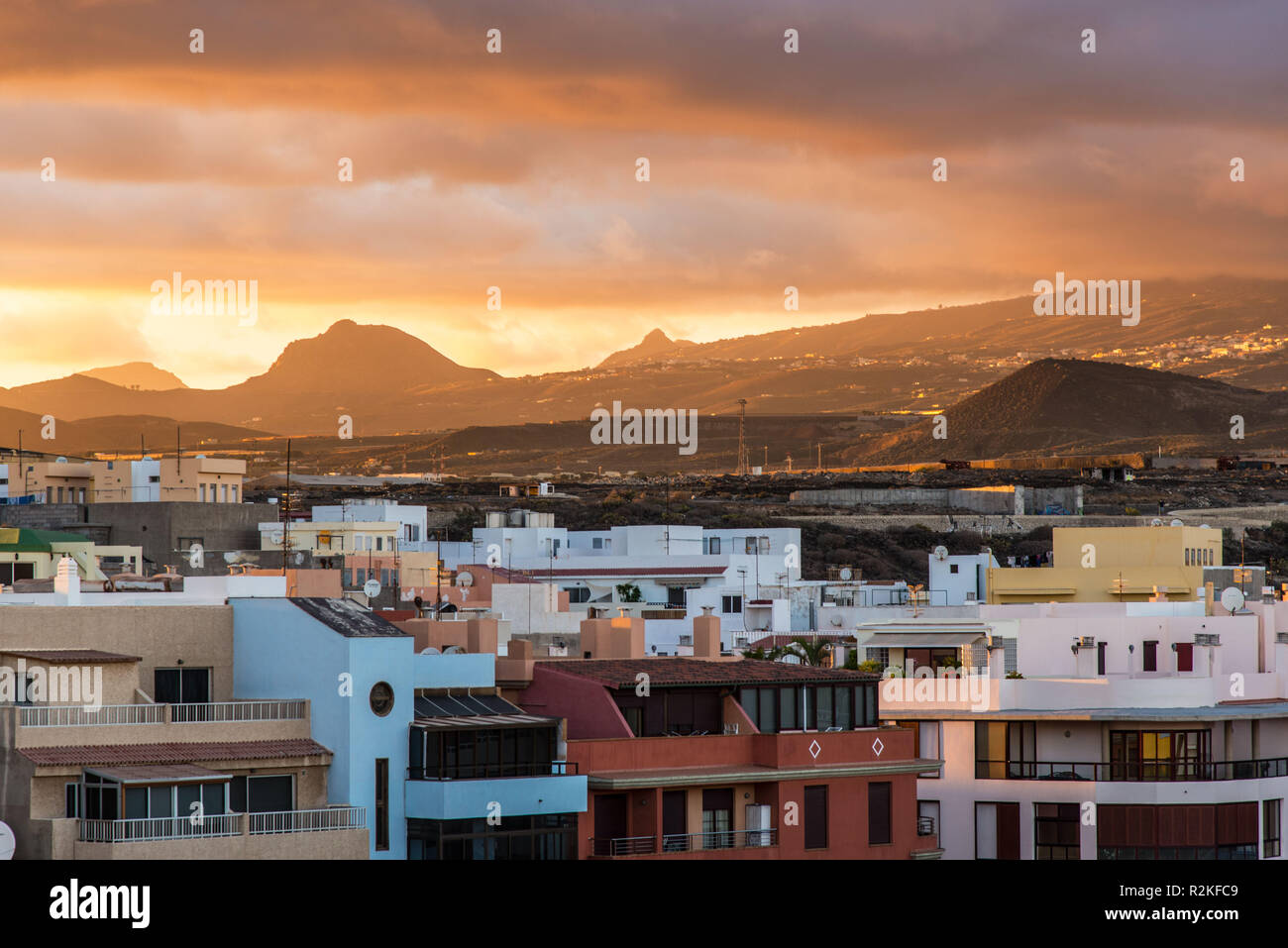 Building of the coastal town of El Medano at sunset in front of the volcanic landscape of Tenerife. Stock Photo