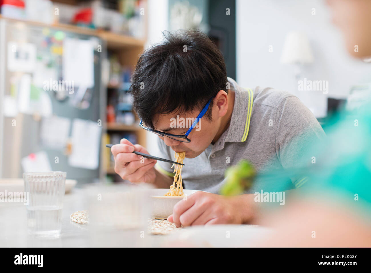 Man eating noodles with chopsticks at table Stock Photo