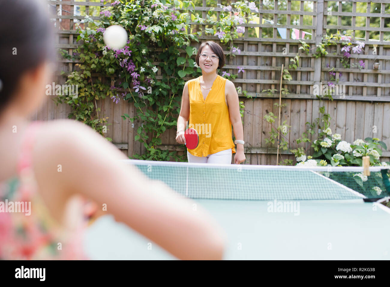 Mother and daughter playing table tennis in sunny backyard Stock Photo